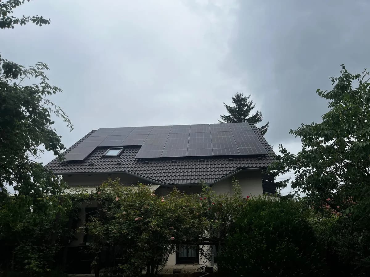 10 kWp Photovoltaik-Anlage auf Satteldach mit grauen Ziegeln und seitlichen Bäumen als Verschattungsquelle in Biesdorf